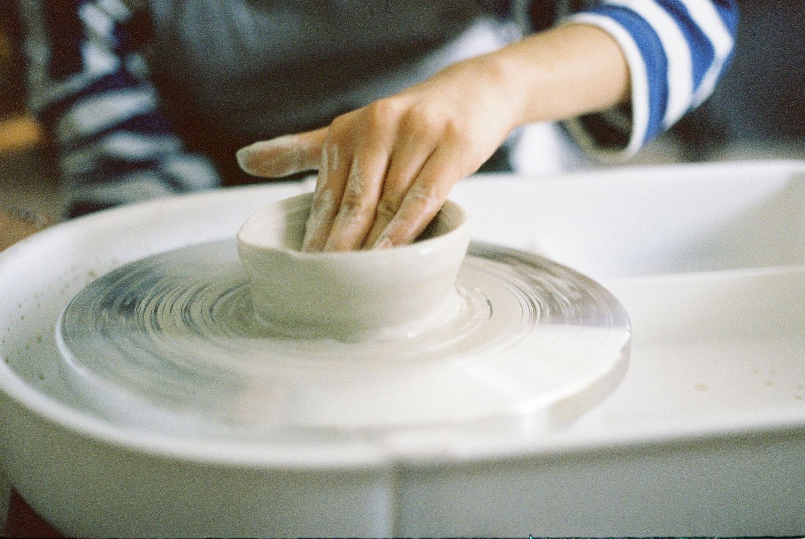 Hands centring clay on a pottery wheel